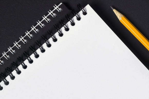 istock Close up of blank notebook and pencil on dark background top view copyspace. 1360552533