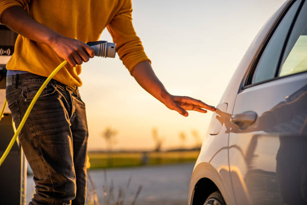 African american man inserting plug into the electric car charging socket