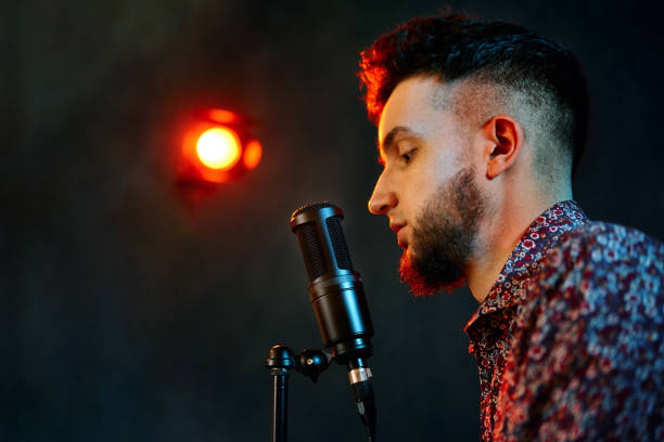 istock Young man singing song on microphone in the studio 1360557127