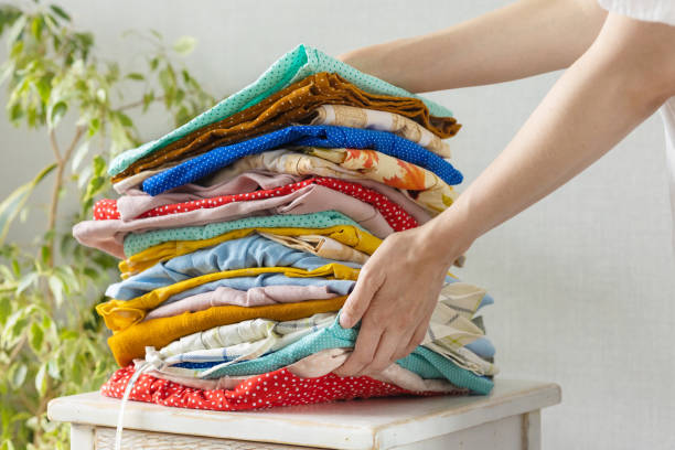 istock women's hands take a stack of clothes from the nightstand for laundry or recycling. children's or adult clothing from the wardrobe 1360557241