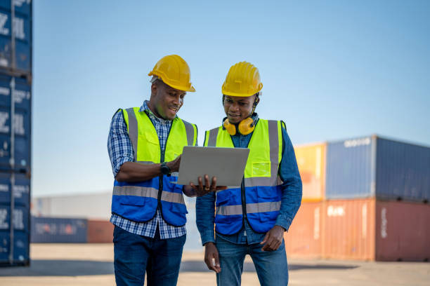 istock African workers, Engineer, Technician holding laptop for checking and inspecting on site containers area for shipping transportation. Concept people operation in heavy industrial. 1360557254