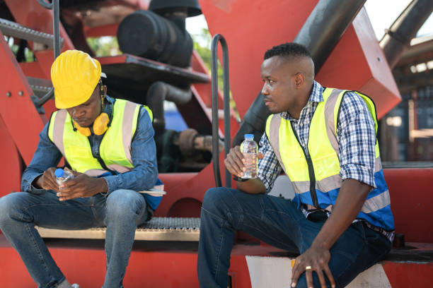 istock African workers, Engineer, Technician sitting and drinking water. people resting after working at the heavy machine vehicle. Concept people operation in heavy industrial. 1360557418