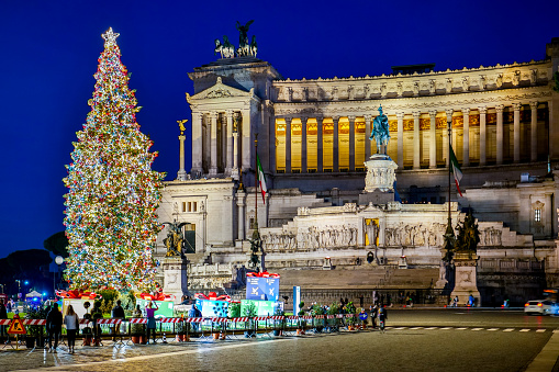 A beautiful and suggestive evening view of Piazza Venezia with a large Christmas tree placed in the center of the square, in the historic center of Rome. In the background the imposing Altare della Patria National Monument. The Altare della Patria or Vittoriano is the Italian National Monument built in 1885 in neoclassical style between the Capitoline Hill or Campidoglio (Roman Capitol) and Piazza Venezia in honor of the first king of Italy, Victor Emmanuel II. Inside is the tomb of the Unknown Soldier, a National War Memorial dedicated to all Italian soldiers who died in the war. Every year the Altare della Patria is the setting for all Italian civic celebrations, in particular the National Day of the Republic on 2 June and the Liberation Day on 25 April. Piazza Venezia is considered the heart of the Eternal City, with the confluence of some of the most important streets of the Italian capital and its proximity to the Roman Forum, the Colosseum and the Campidoglio (Roman Capitol). In 1980 the historic center of Rome was declared a World Heritage Site by Unesco. Image in high definition format.