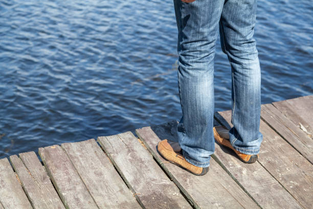 les jambes en jeans se tiennent sur un pont en bois au-dessus de la rivière - horizon over water horizontal surface level viewpoint photos et images de collection