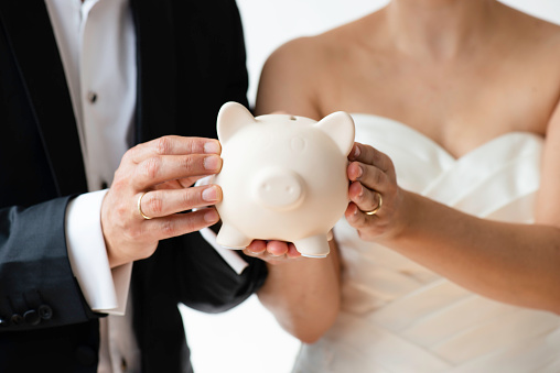 Bride and groom holding piggy bank.
