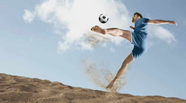 The man footballers are desperately playing beach soccer on sand on a sunny day stock photo