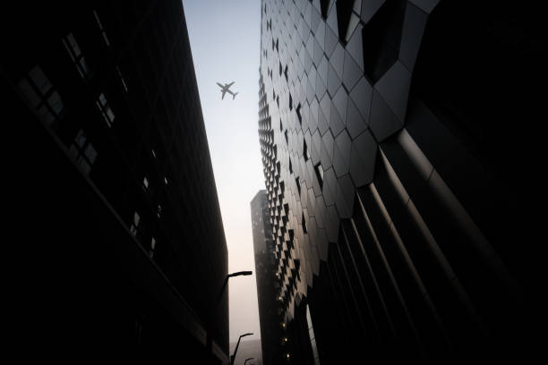 istock Aeroplane jumbo jet passenger plane flying between modern city centre sky scrapers 1360569928