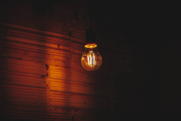 istock Led light bulb on, in a dark room with a white wall 1360574064