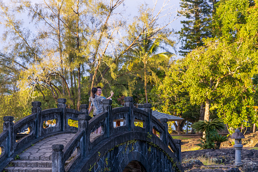 Hilo, Hawaii - November 27, 2021: Beautiful Liliuokalani Park and Gardens in Hilo, Hawaii, on a rainy sunset. Young couple taking pictures.