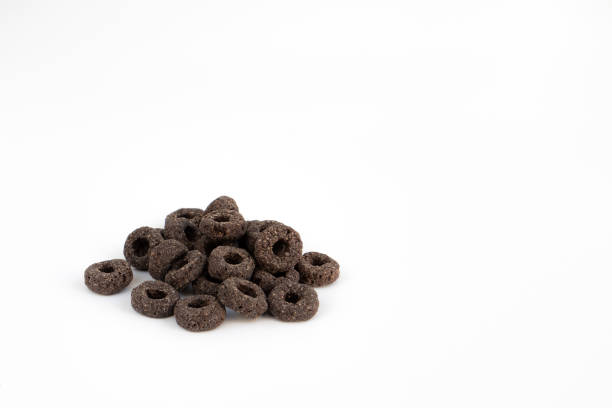 heap of black cereal rings isolated on white background, delicious and useful rings breakfast cereal, side view closeup