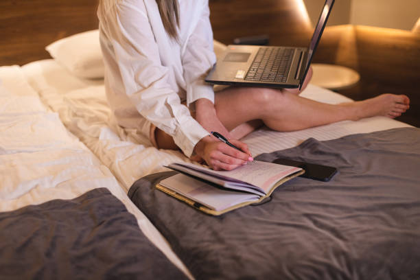 istock Close up of a young businesswoman writing down notes in her notepad while working from a hotel room 1360583414