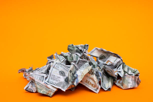 istock Crumpled 100 dollars falling on a orange color background 1360585437