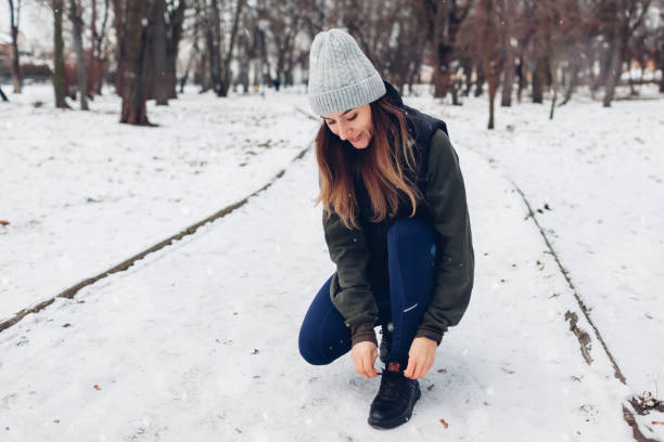 istock Runner tying shoe laces in snowy winter park. Woman training working out outdoors. Active healthy sportive lifestyle 1360586582