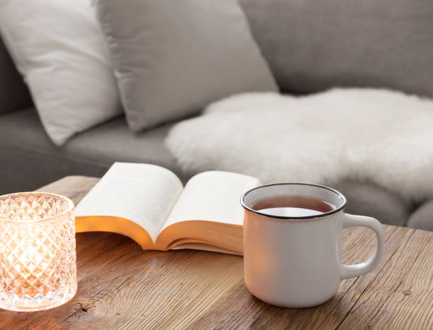 Cozy living room Cozy afternoon reading on the sofa with a steaming cup of tea hygge stock pictures, royalty-free photos & images