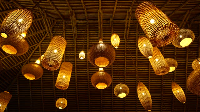 A lot of wicker lampshades on the ceiling of a wooden house