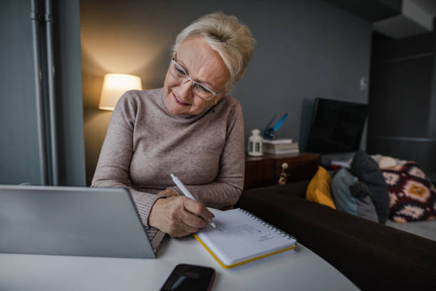 istock Senior woman at home, using laptop 1360588993