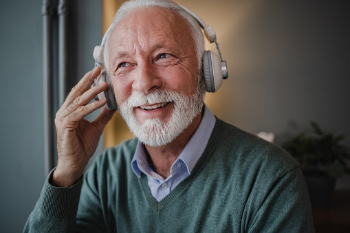 Senior man at home, listening music on the headphones