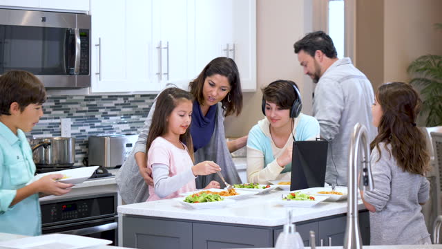 Multiracial family with four children eating in kitchen