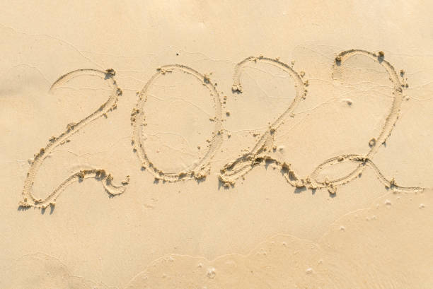 istock handwritten lettering 2022 on sandy beach 1360596230