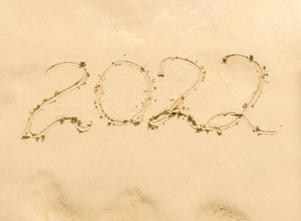 istock inscription 2022 on yellow sand close up. 1360596236