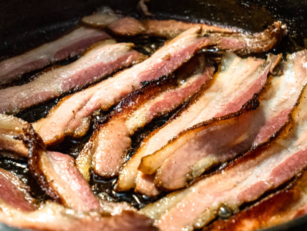 istock Pork bacon frying in a cast iron skillet pan 1360597314
