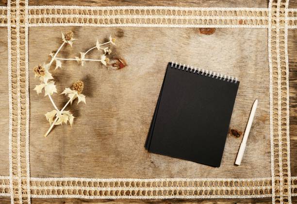 istock New year concept, black notebook and pen on a wooden background. 1360599088
