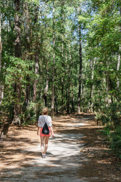 istock Woman on a path on a sunny day among green trees 1360606515