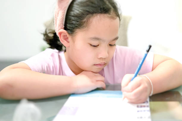 istock female girl is writing on table while learning at home 1360616012