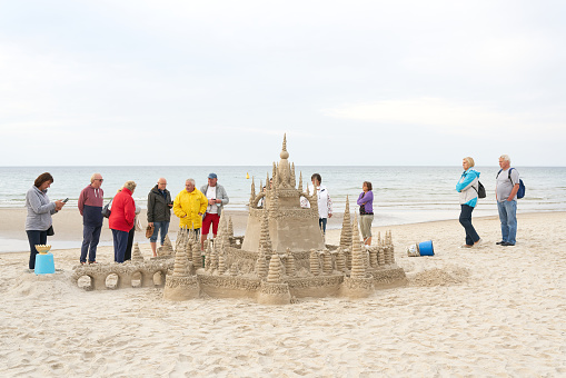 Kolobrzeg, Poland – September 06, 2021: Holidaymakers admire a sandcastle on the beach of Kolobrzeg on the Polish coast of the Baltic Sea