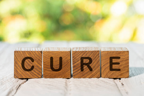 cubos de madera de teca con la palabra 'cure' escrita en ellos, sentados en una mesa de madera blanca desgastada, sobre un fondo de jardín desenfocado. - organic single word environment block fotografías e imágenes de stock