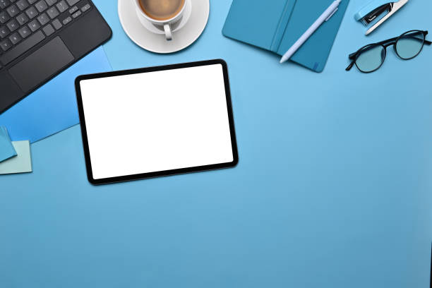 istock Mock up digital tablet, coffee cup and supplies on blue background. 1360628890