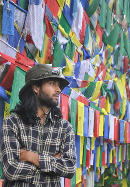 istock A good looking young guy looking sideways posing with his arms crossed, standing against Buddhist prayer flags 1360635290