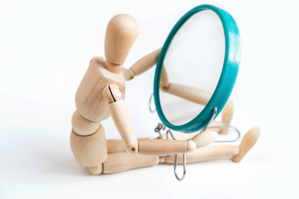 istock Wooden dummy looks at its reflection in the mirror 1360641664