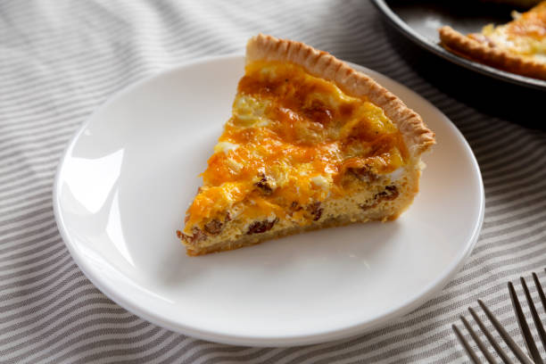 istock Homemade Bacon Quiche with Eggs and Cheddar Cheese on a white plate, low angle view. Close-up. 1360643341