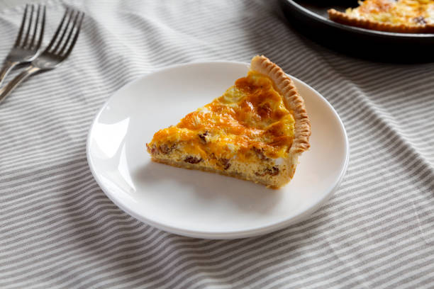 istock Homemade Bacon Quiche with Eggs and Cheddar Cheese on a white plate, side view. 1360643537