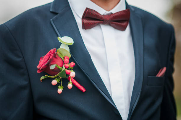 Dark red bowtie on grooms neck and red rose on the jacket