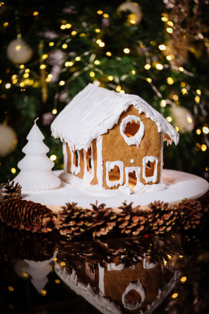 istock Gingerbread house on a table with Christmas tree in blurry background and reflection 1360647792