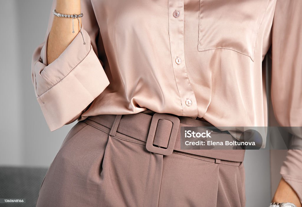 Classic business style of clothing. Palazzo trousers with a wide belt and a silk blouse. Powdery pink color. A combination of shades of color in clothing. Women Stock Photo