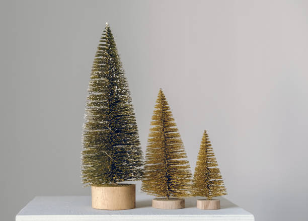 istock Selective focus tiny golden Christmas trees on a white background. Copy space. Christmas minimal card. 1360648897