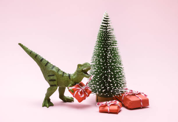 istock Funny plastic toy dinosaur  with  present boxes on a pink background. 1360648981