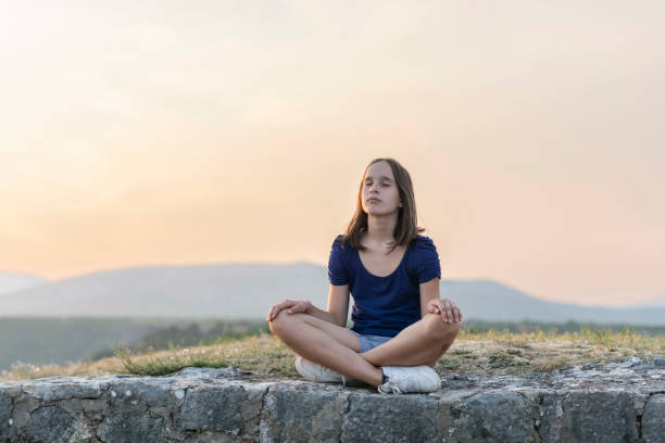 istock Girl meditating at sunset 1360649883
