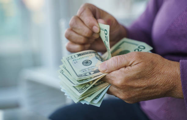 istock Senior woman counting US Dollar banknotes, Close up 1360651822
