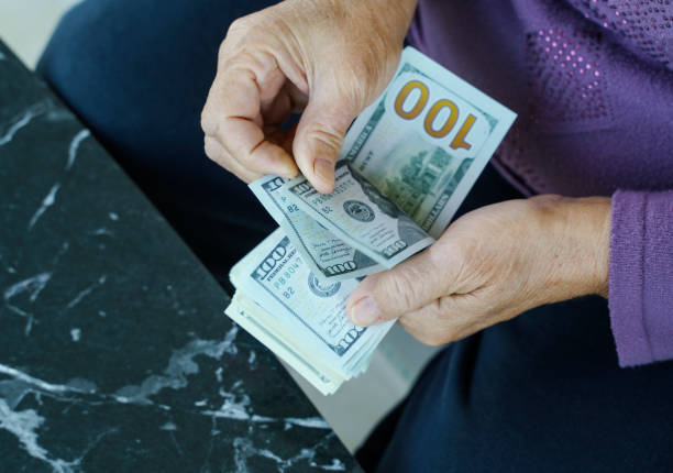 istock Senior woman counting US Dollar banknotes, Close up 1360651823