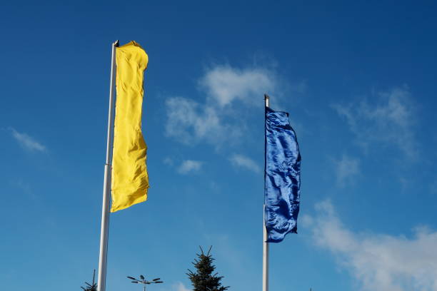 화창한 ��날에는 두 개의 깃발이 노란색과 파란색으로 하늘을 가로질러 바람에 펄럭입니다. - two flags 뉴스 사진 이미지