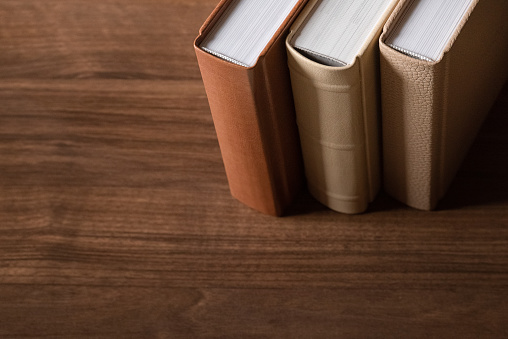 Spines of books in leather hardcovers on wooden background