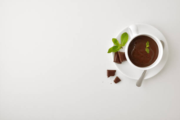 hintergrundbecher mit flüssiger schokolade mit minze auf weißem tisch - hot chocolate hot drink high section color image stock-fotos und bilder
