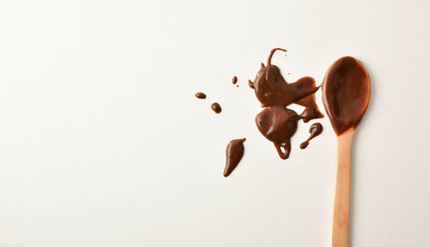 hintergrund mit schokoladenbeflecktem küchenlöffel auf weißem tisch - hot chocolate hot drink high section color image stock-fotos und bilder