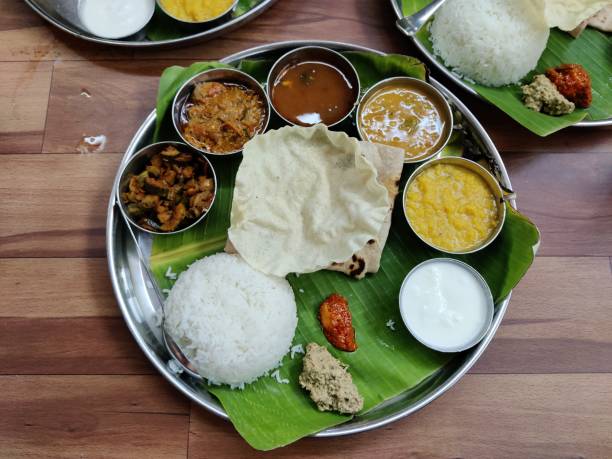 Traditional banana leaf rice (curry on rice with pumpkin, cucumber, deep fried snakegourd, pappadom and rasam). Malaysian culture is to eat with clean bare right hand instead of using cutleries.