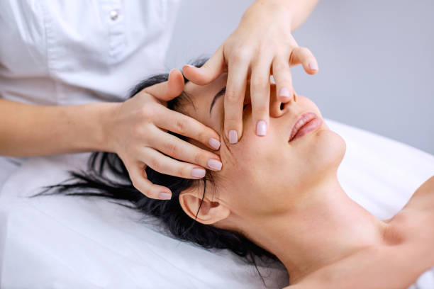 massaggio viso e testa per una giovane donna. metodi di salute alternativi con oli aromatici. procedure di cosmetologia per la pelle del viso e del corpo. cura della pelle in età adulta. foto orizzontale - massaging facial massage beautician beauty treatment foto e immagini stock