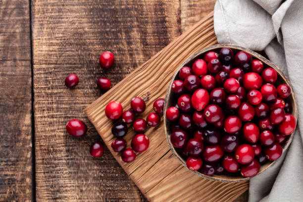 istock Red cranberries on wooden background. Brries in a bowl. 1360658345